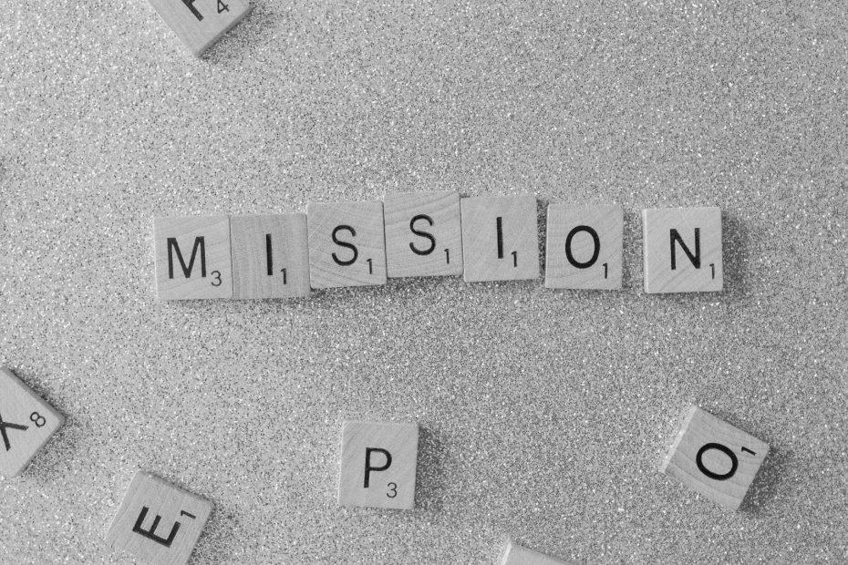 Scrabble tiles spelling 'MISSION' on a glittery surface, a symbolic and creative concept.